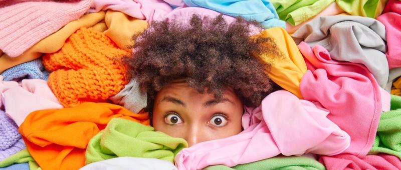 Une femme afro-américaine surprise est ensevelie dans des vêtements de blanchisserie aux couleurs vives.