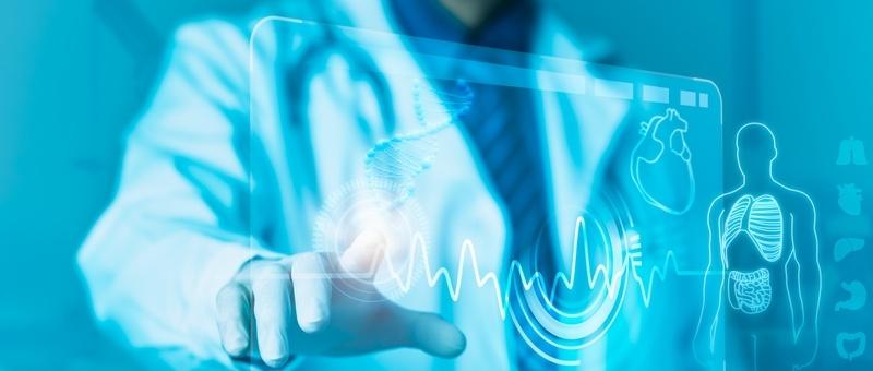 Professionnel médical en blouse blanche touchant l'interface numérique montrant le rythme cardiaque et l'anatomie humaine dans les tons bleus.
