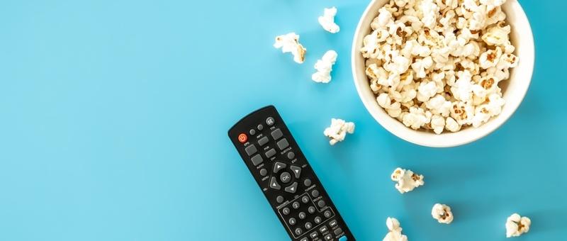 Télécommande de télévision et pop-corn sur fond bleu.