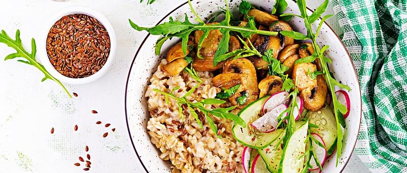 Petit-déjeuner porridge d'avoine aux herbes vertes sur champignons, concombre, radis et graines de lin.