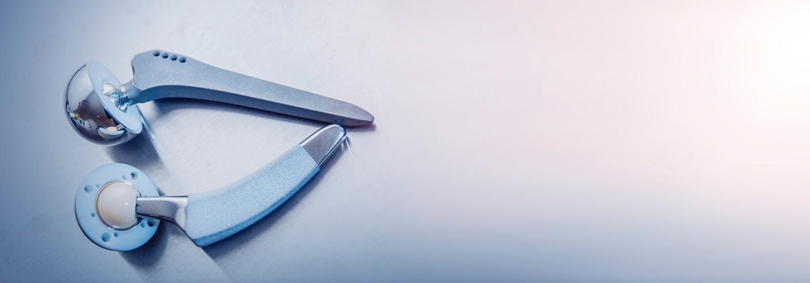 Medical device showing two metallic components of a joint implant on light blue background.