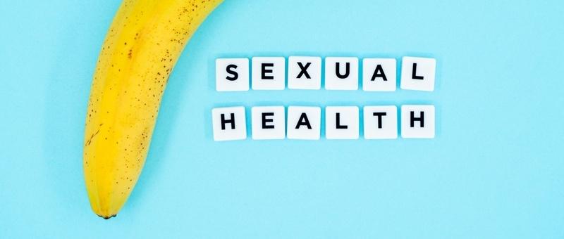 Type led - SEXUAL HEALTH imprimé sur des blocs blancs à côté d'une banane sur fond bleu.