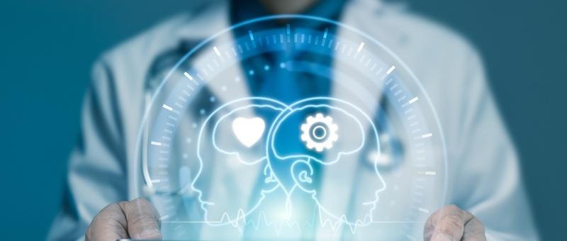 Professionnel de la santé tenant un hologramme numérique montrant deux têtes de profil avec des symboles de cœur et d'engrenage représentant la technologie des soins de santé.