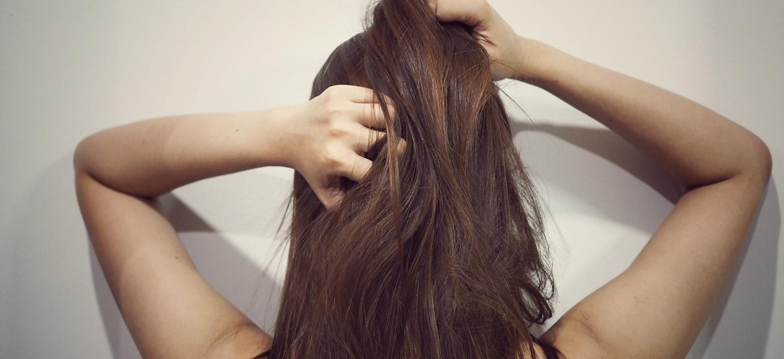 Une femme se gratte l'arrière de la tête.