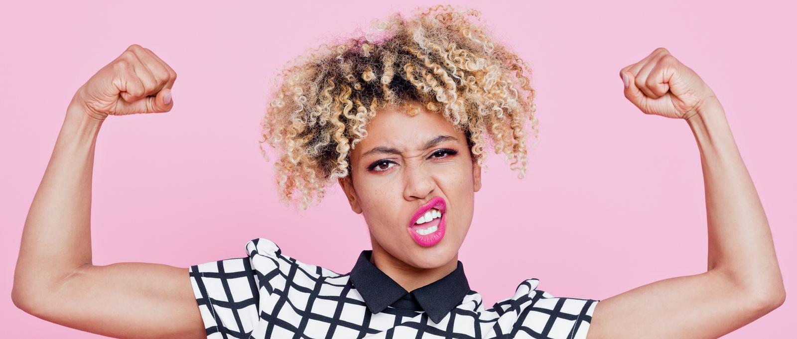 Portrait de studio d'une jeune femme afro-américaine forte qui fait des flexions musculaires.