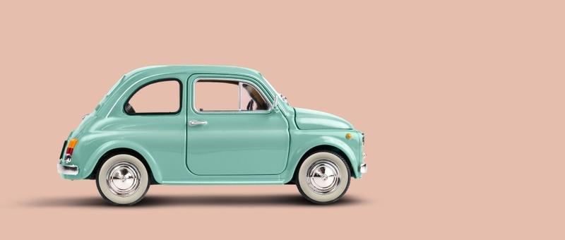 Model green retro toy car on pink peach background.