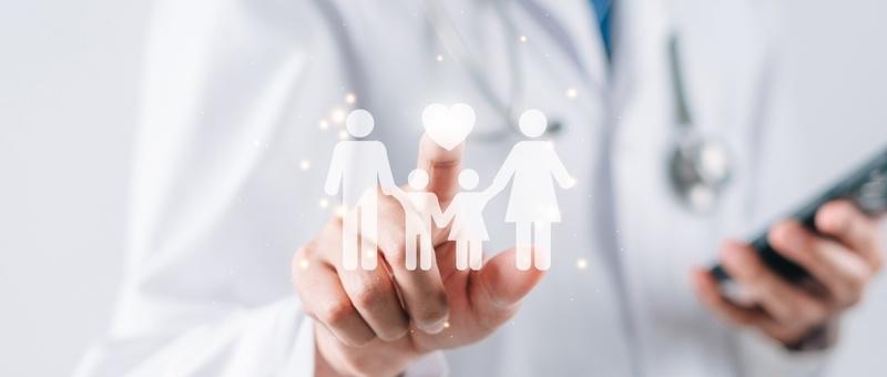 Professionnel de la santé en blouse blanche tenant une icône de famille numérique tout en utilisant un smartphone dans l'autre main.