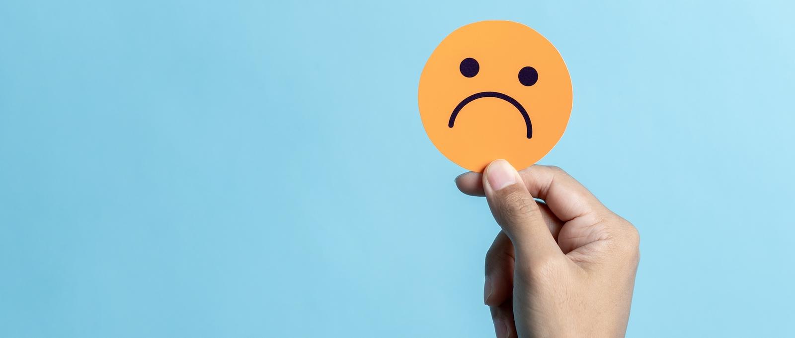 Un cercle orange avec un visage triste sur un fond bleu.