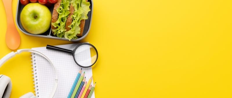 Déjeuner à emporter avec des outils d'étude sur fond jaune.