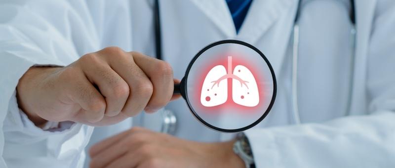 Professionnel de la santé en blouse blanche tenant une loupe et montrant un poumon rougeoyant.