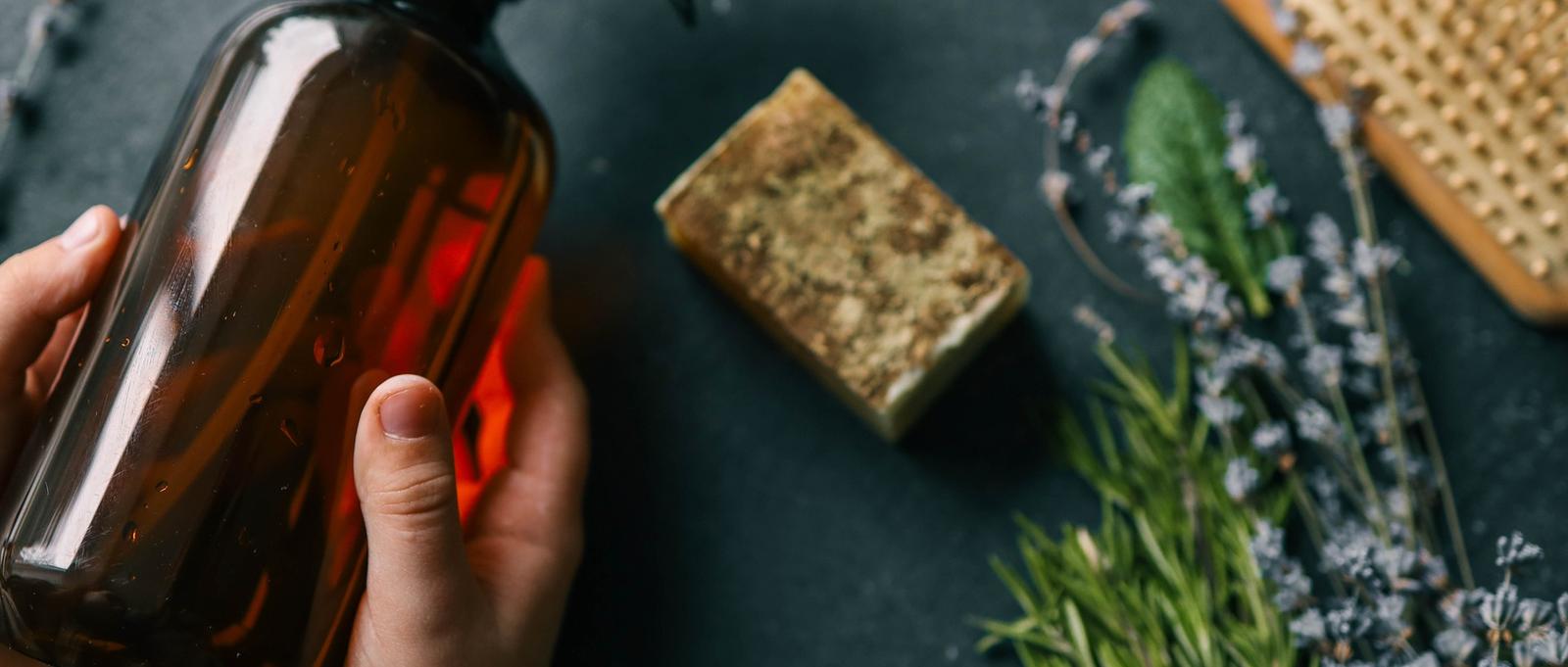 Spray naturel pour la croissance des cheveux avec des herbes dans les mains.