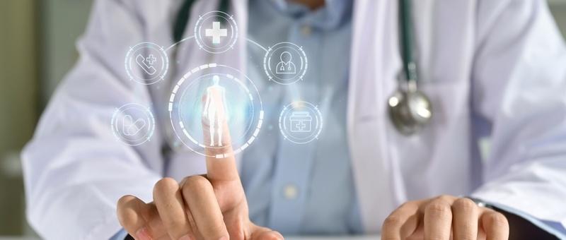 Médecin avec stéthoscope touchant une interface numérique de soins de santé montrant une silhouette humaine et des icônes médicales.