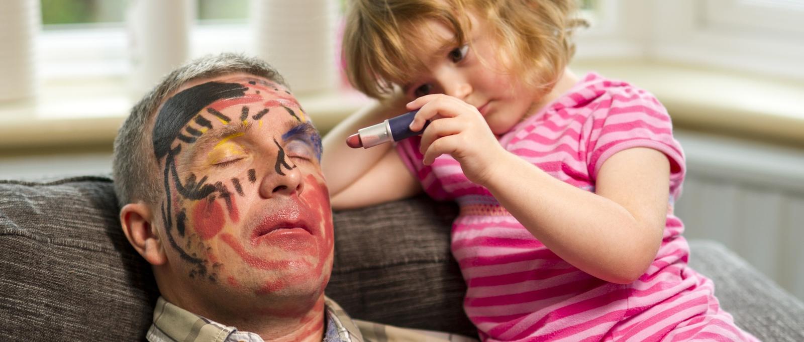 Petite fille dessinant sur le visage de son père endormi