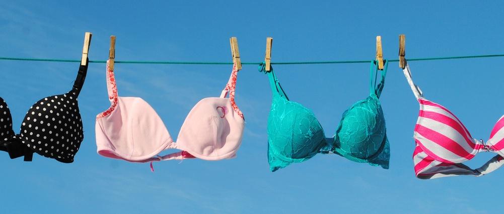 Quatre soutiens-gorge colorés sur une corde à linge