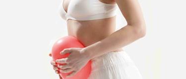 Woman clutching a balloon to her stomach to symbolise trapped wind.