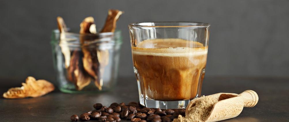 Mushroom coffee in a glass, coffee beans and dry mushrooms on a dark background.