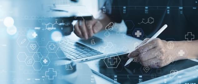 Personne travaillant sur un ordinateur portable et une tablette numérique avec des icônes médicales et des graphiques de soins de santé superposés dans des tons bleus.