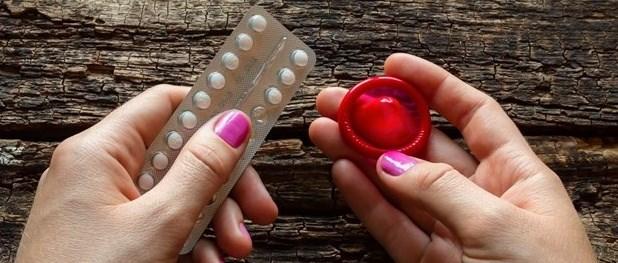 Une femme tenant la pilule contraceptive et un préservatif rouge