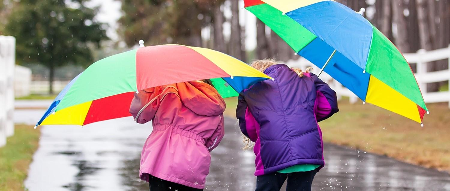 Enfants jouant dans les flaques d'eau en tenant un parapluie