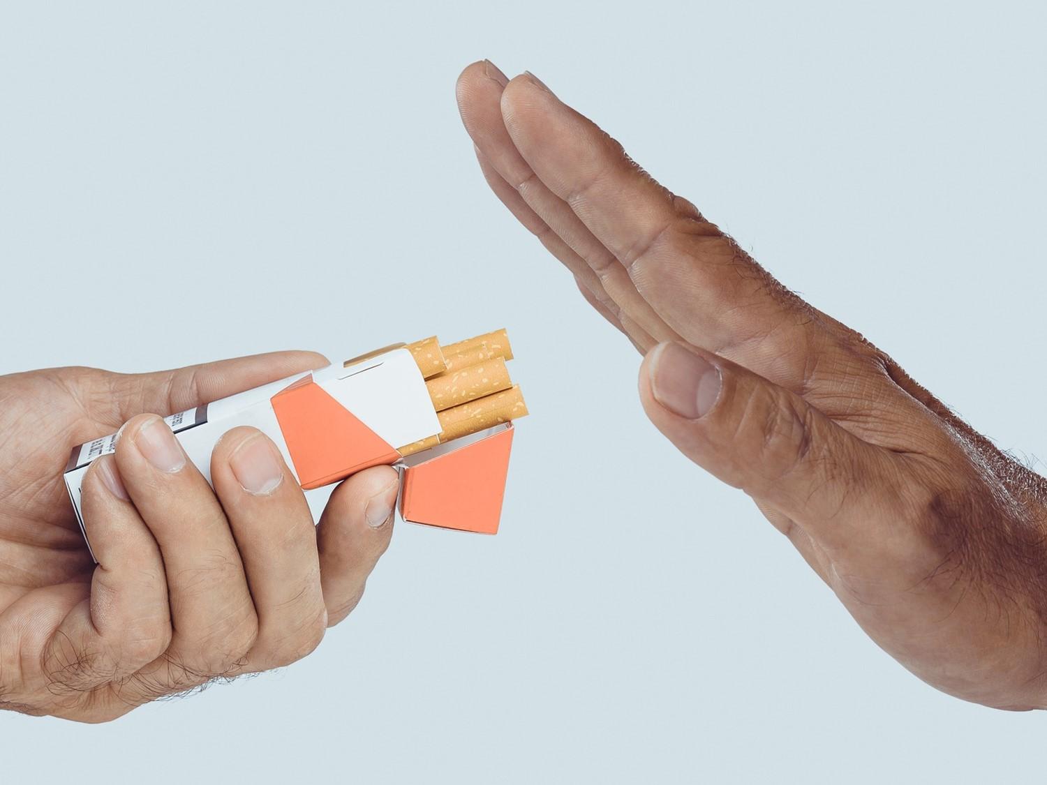 Geste de la main s'arrêtant à une autre main offrant un paquet de cigarettes, symbolisant l'arrêt du tabac ou le refus.