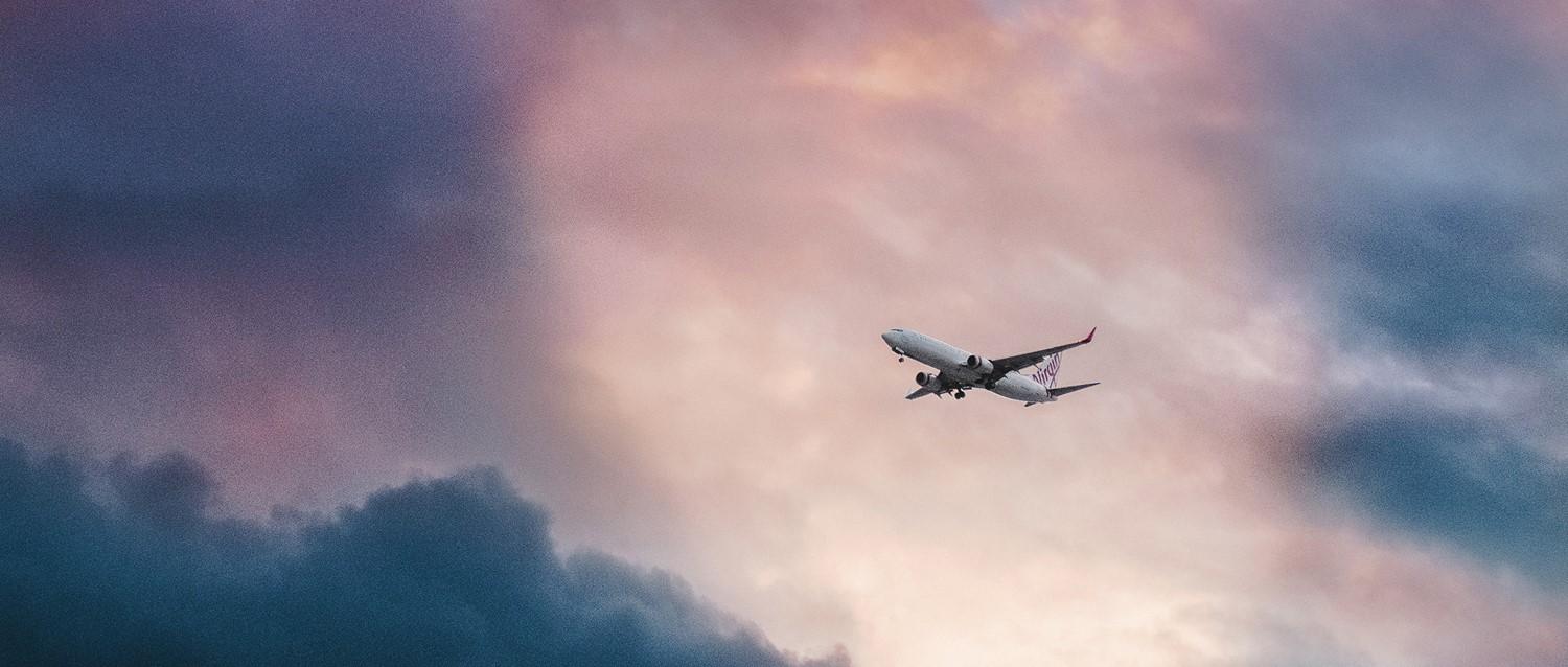 Avion vierge volant dans un ciel nuageux rose et bleu au crépuscule.
