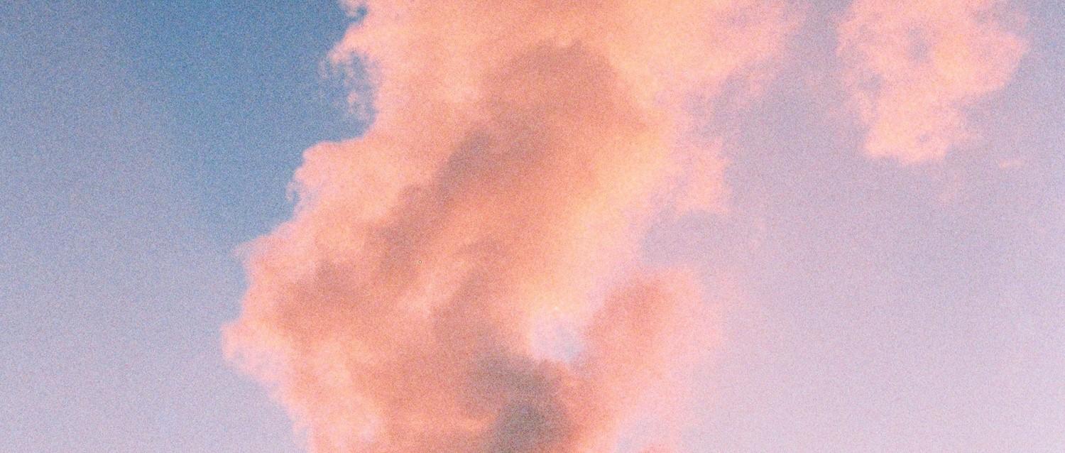 Formation de nuages roses sur un ciel bleu au coucher du soleil, créant une atmosphère pastel et rêveuse.